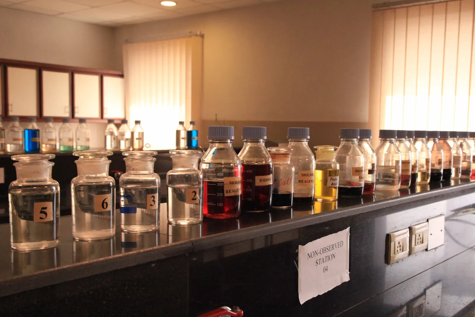 Laboratory shelf lined with reagent bottles and chemical solutions
